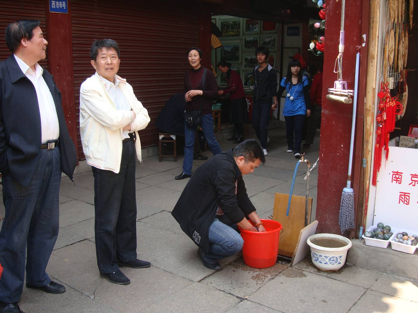 In the middle of the tourist shops, what's in the bucket?  Temple market area, Nanjing, China