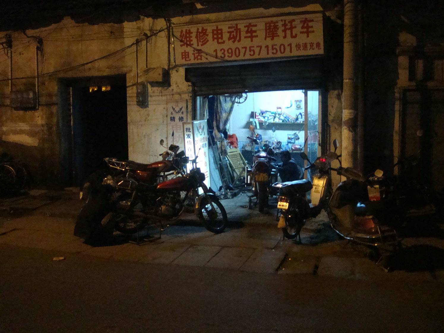 Picture:  Motorcycle maintenance goes late into the evening.  Haikou on Hainan Island, China