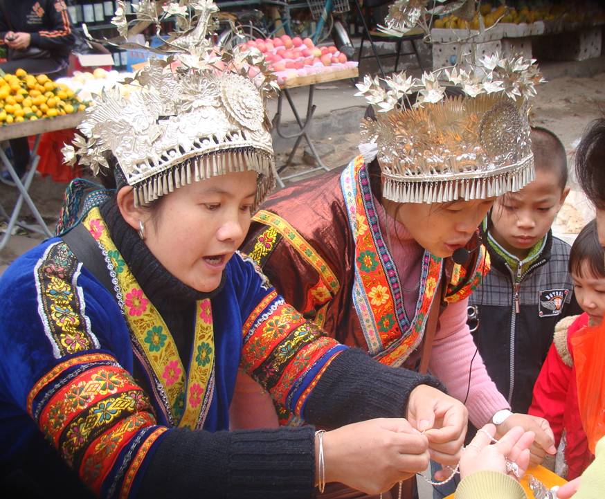 Picture:  Young ethnic minority girls sell their silver jewelry outside the gates of Hainan Normal University.  Haikou on Hainan Island, China