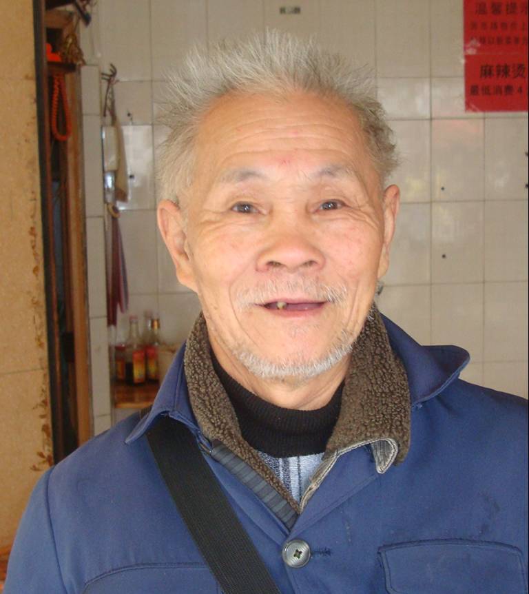 Picture:  The restaurant owner, and a fine set of tooth he has. He was kind enough to take his cigarette out to the street when I asked him to. Haikou, Hainan Island, China