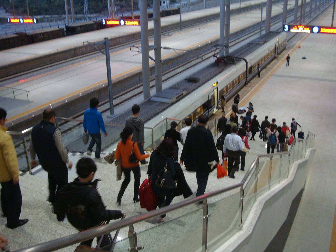 Picture:  Passengers stream down the stairs to the new fast train in the Sanya station.  Sanya, Hainan Island, China