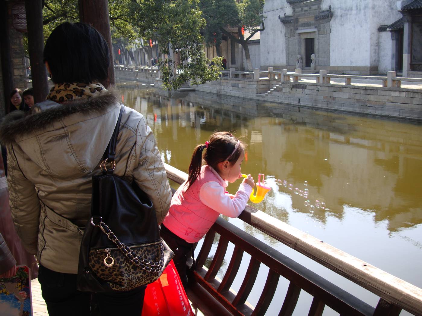 Picture:  A child blows bubbles over the canal.  Wuxi, China