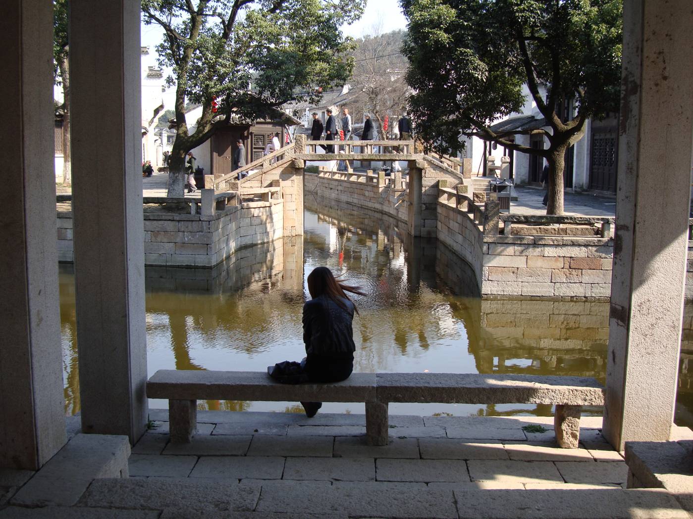 Picture:  A girl waits beside the sunlit canal.  Wuxi old city, Wuxi, China