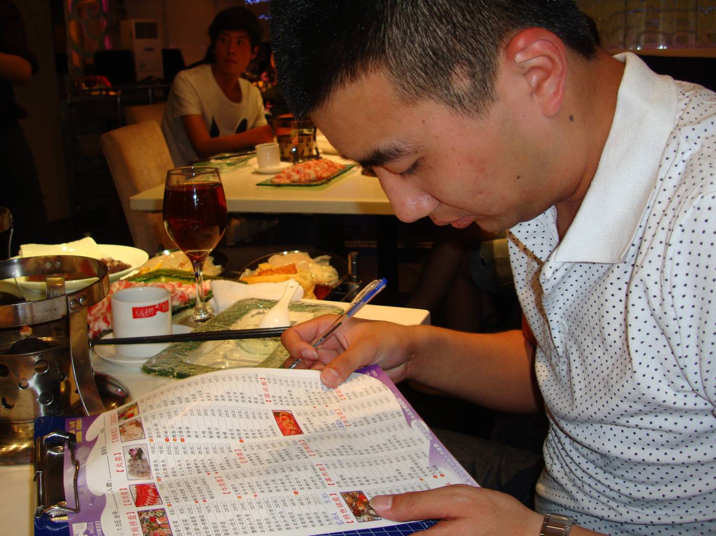 Picture:  Clark scans the menu before ordering for all of us.  Hotpot dinner in Wuxi, China