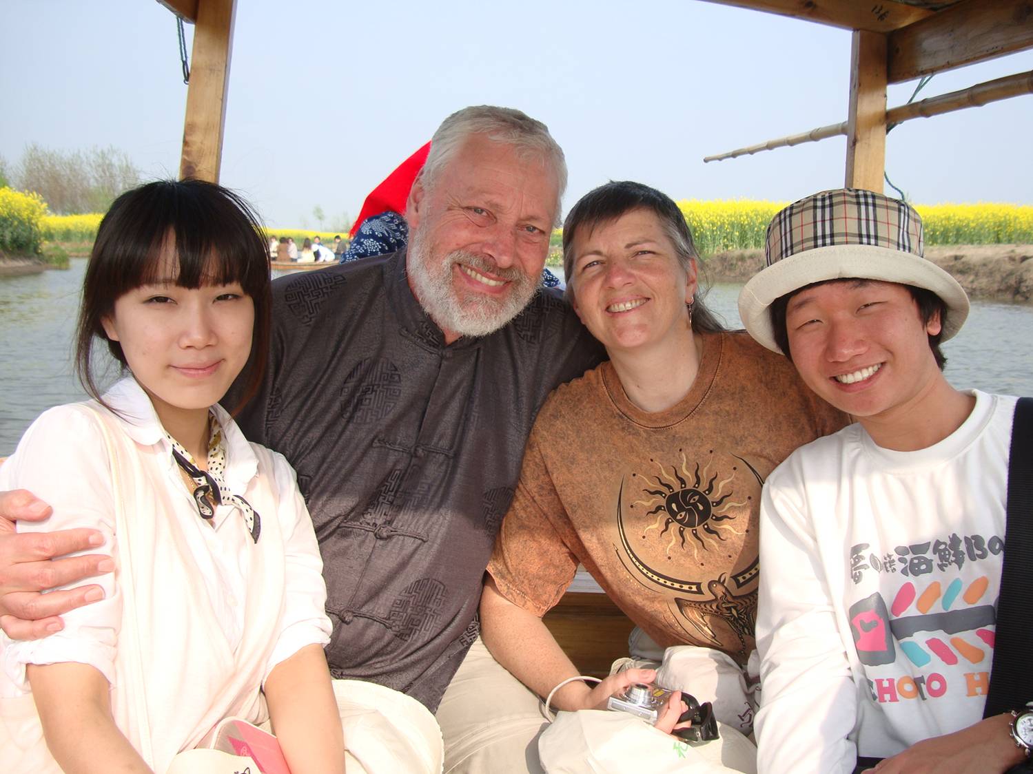 David and Ruth center with two Korean students.  In a boat.  Being rowed through the canola fields.  In China.