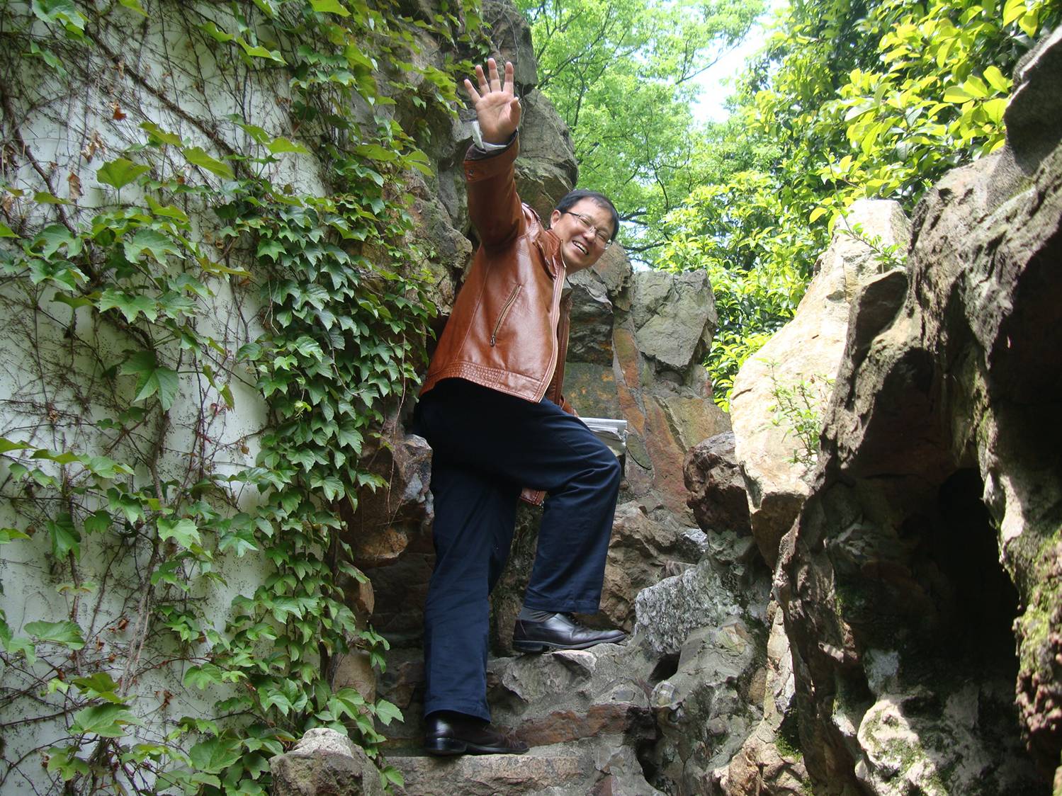 Simon Yang on rocks he climbed as a boy.  Contentment Garden,  Xi Hui Park,  Wuxi,  China