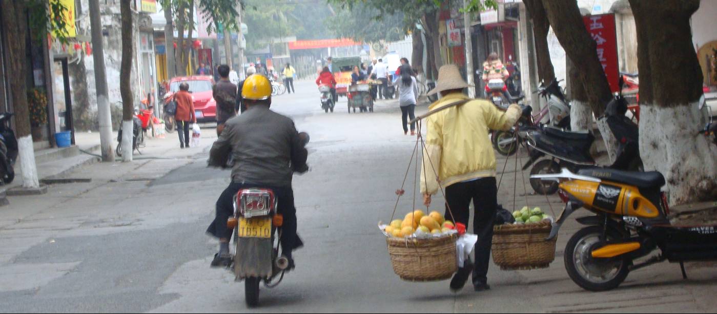 Picture:  A woman carries a heavy load of fruit to the market in Haikou, Hainan Island, China