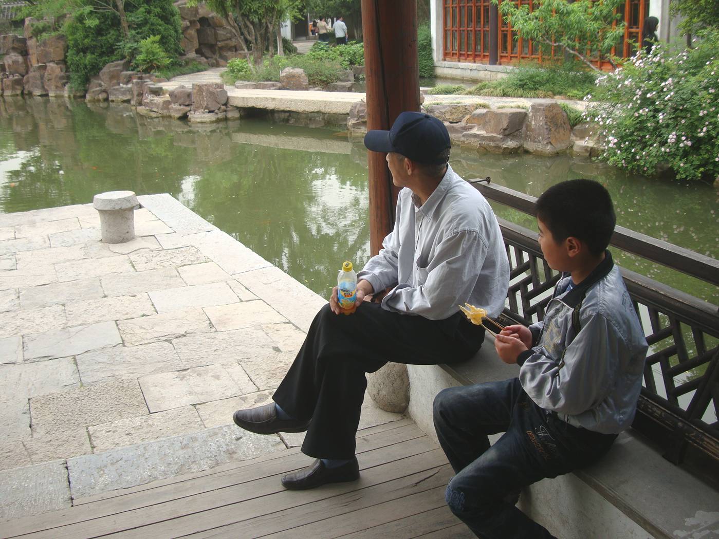 Picture:  A father and son take a minute to enjoy the serenity of the pond.  The museum grounds near Xi Hui Park, Wuxi, China