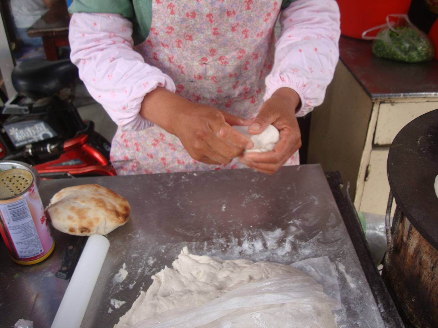 Picture:  The wife rolls out the dough, takes care of the baking, and collects the money.  Shi Tang Cun, Wuxi, China