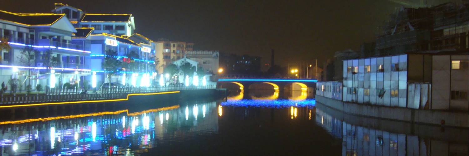 New construction on the left, workers' quarters on the right.  Wuxi, China, canal at night.